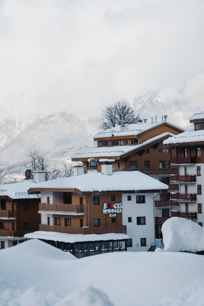 story-01 Charming mountain resort buildings blanketed in snow against a serene winter backdrop.