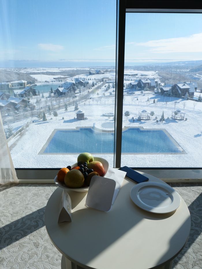 services-01 Sunlit winter landscape at a resort with pool, snow, and fruit on a table.